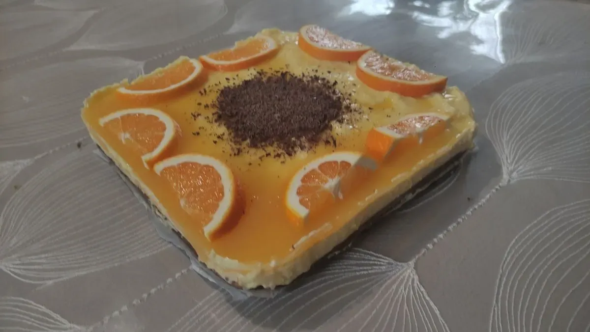 Kolač sa kremom i kriškama narandže, posut čokoladom