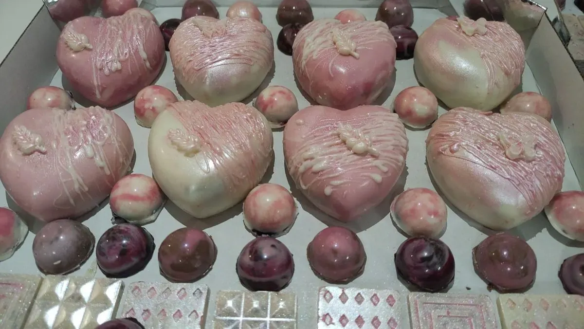 Čokoladna srca u roze i belim tonovima i čokoladne polulopte poređane u kutiji