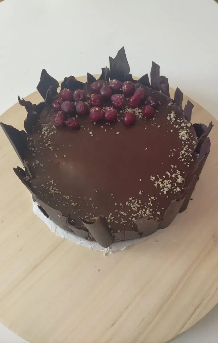 Čokoladna torta ukrašena čokoladnim listićima i višnjama