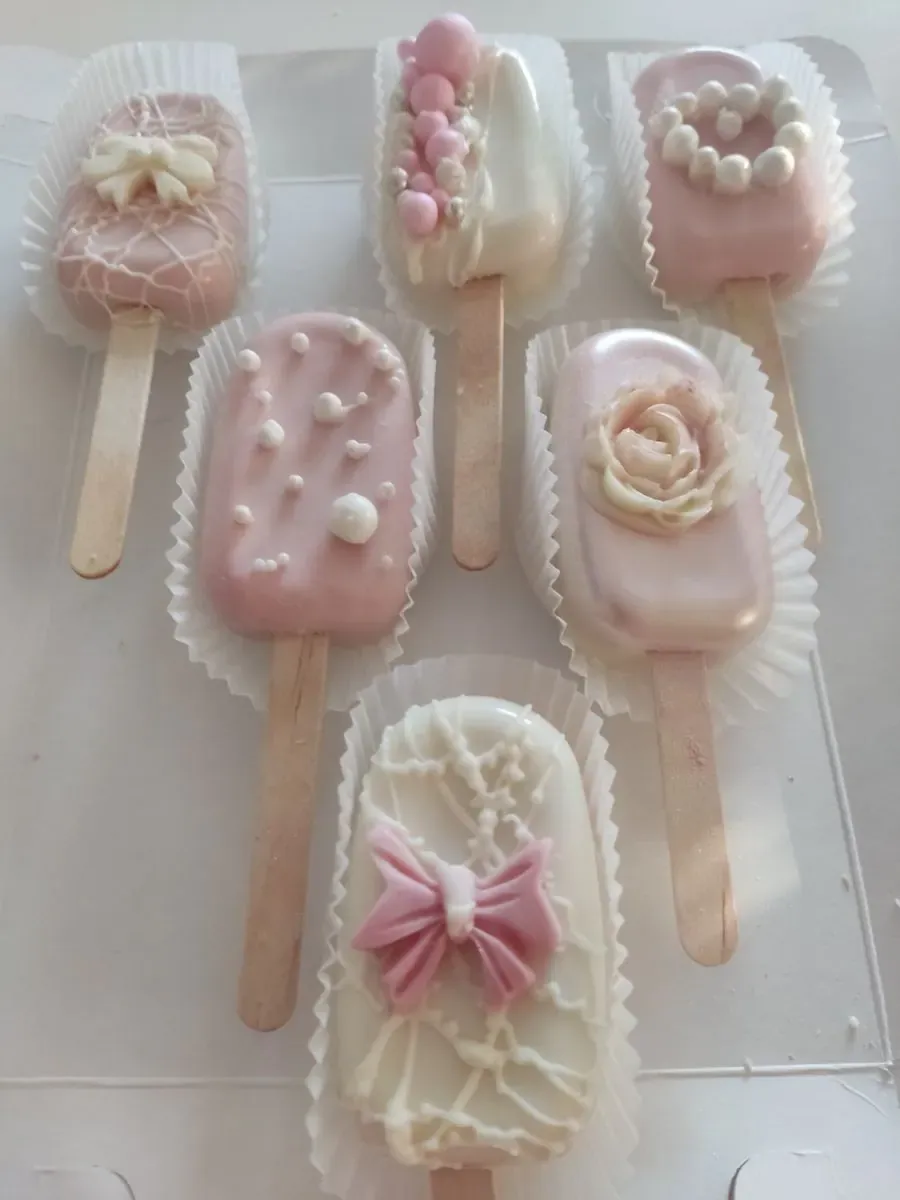 Roze i beli pops sladoledi ukrašeni mašnom, perlicama i čokoladnom ružom