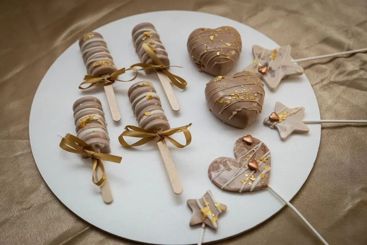 Čokoladni pops sladoledi, srca i zvezdice sa zlatnim detaljima na beloj tacni