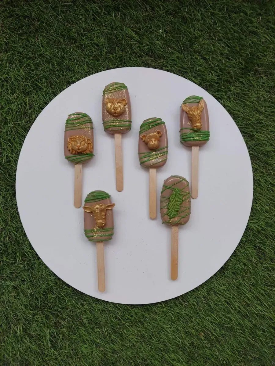 Čokoladni pops sladoledi sa zlatnim figurama životinja i zelenim linijama, tema džungle