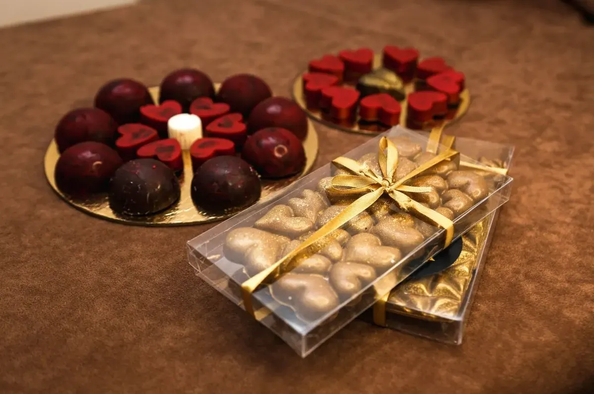 Praline u obliku srca na zlatnim tacnama i čokoladna tabla sa zlatnim srcima u poklon kutiji